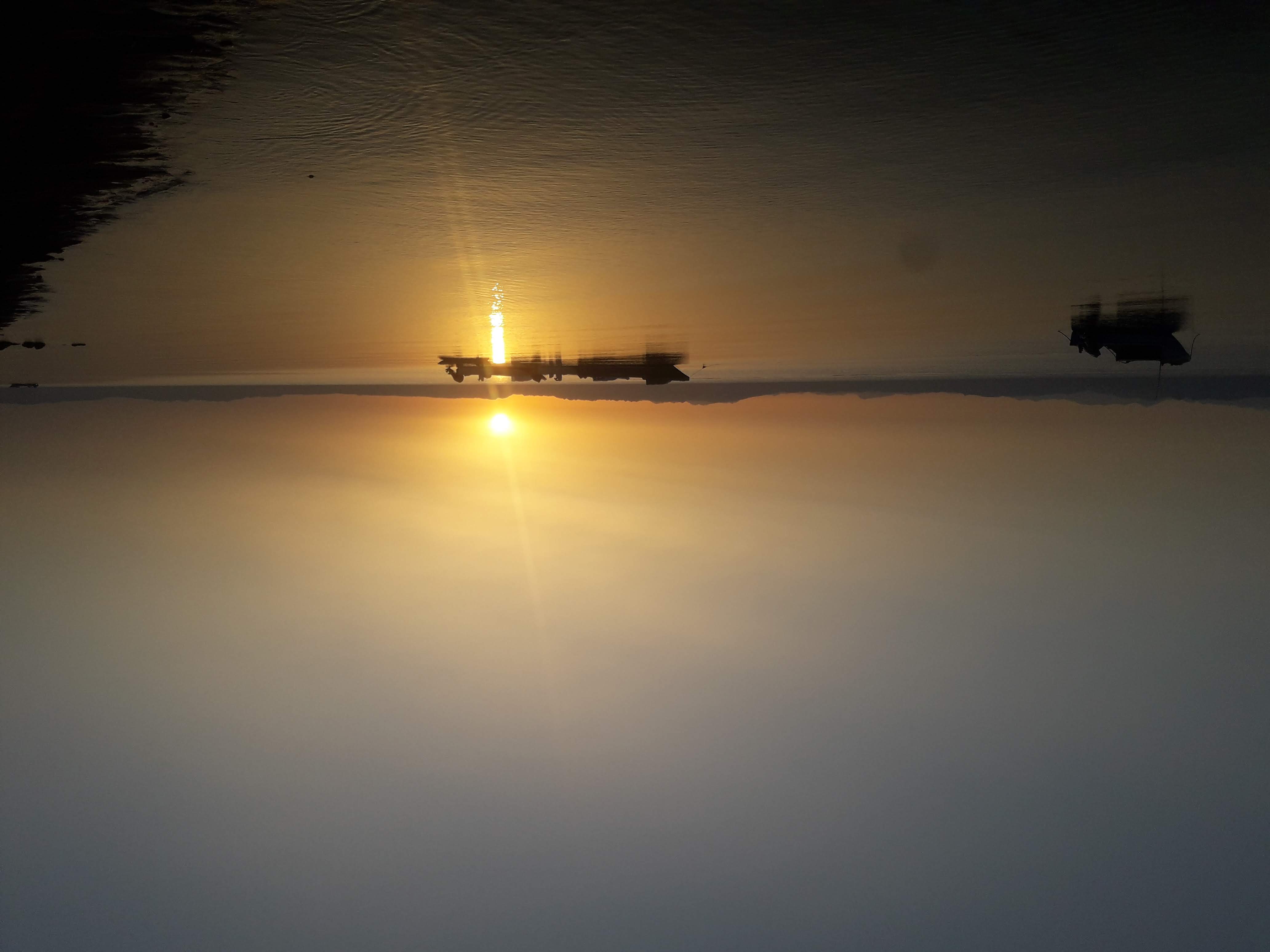 Sunset over water with two boats, symbolizing hope and renewal